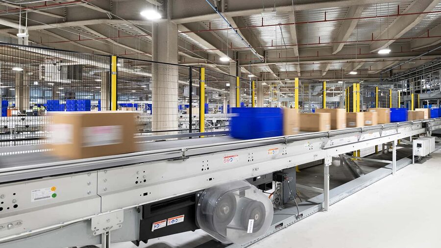 Material handling conveyor line in a distribution center, built from fabricated sheet metal side frames and guarding.