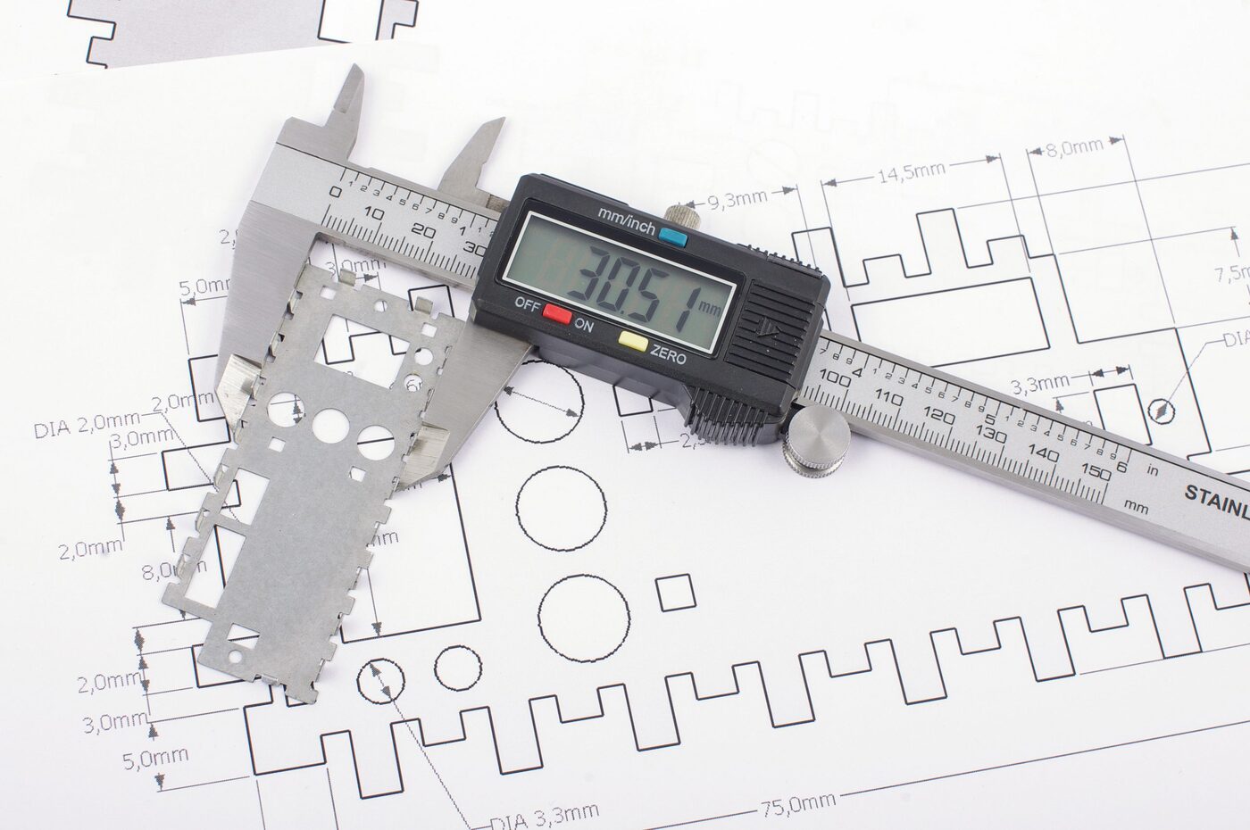 Precision calipers measuring a machined sheet metal part in the SPM quality lab