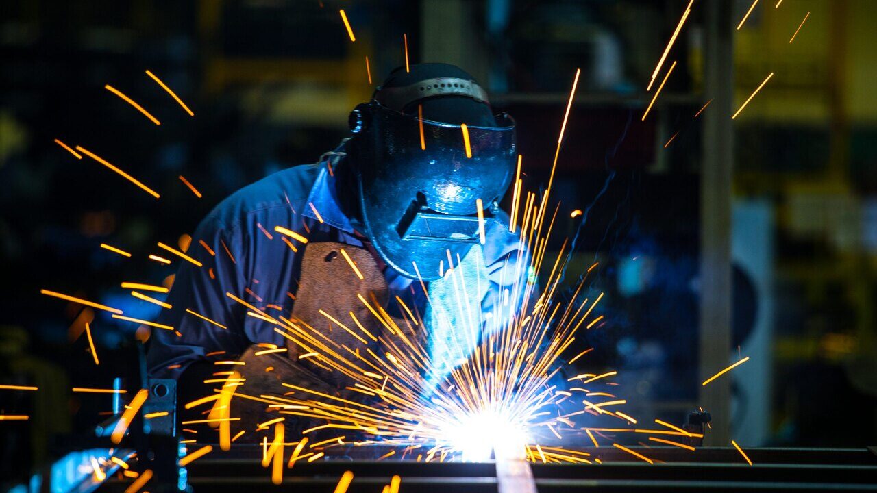 Certified welder running a manual arc weld on a steel weldment at SPM