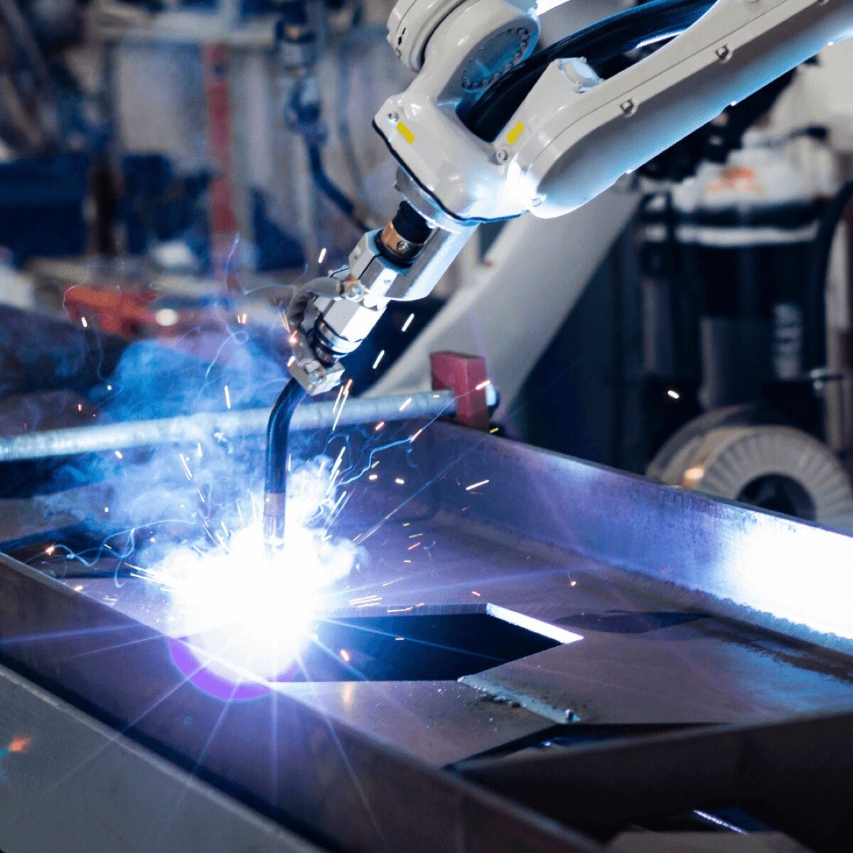 Robotic welding cell producing a bright arc while welding a steel weldment on the SPM welding floor