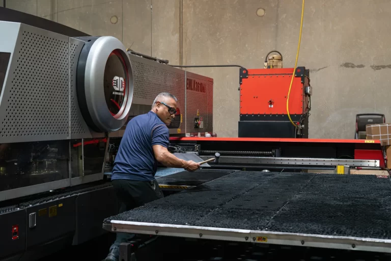 Operator removing punched parts from a sheet skeleton at an Amada EML-K punch/laser combination machine